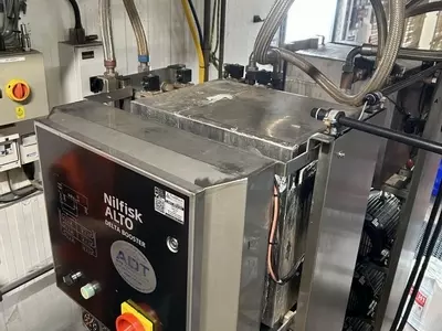 Original water tank installed on Nilfisk Delta Booster multi-pump pressure washer system before stainless steel tank replacement.